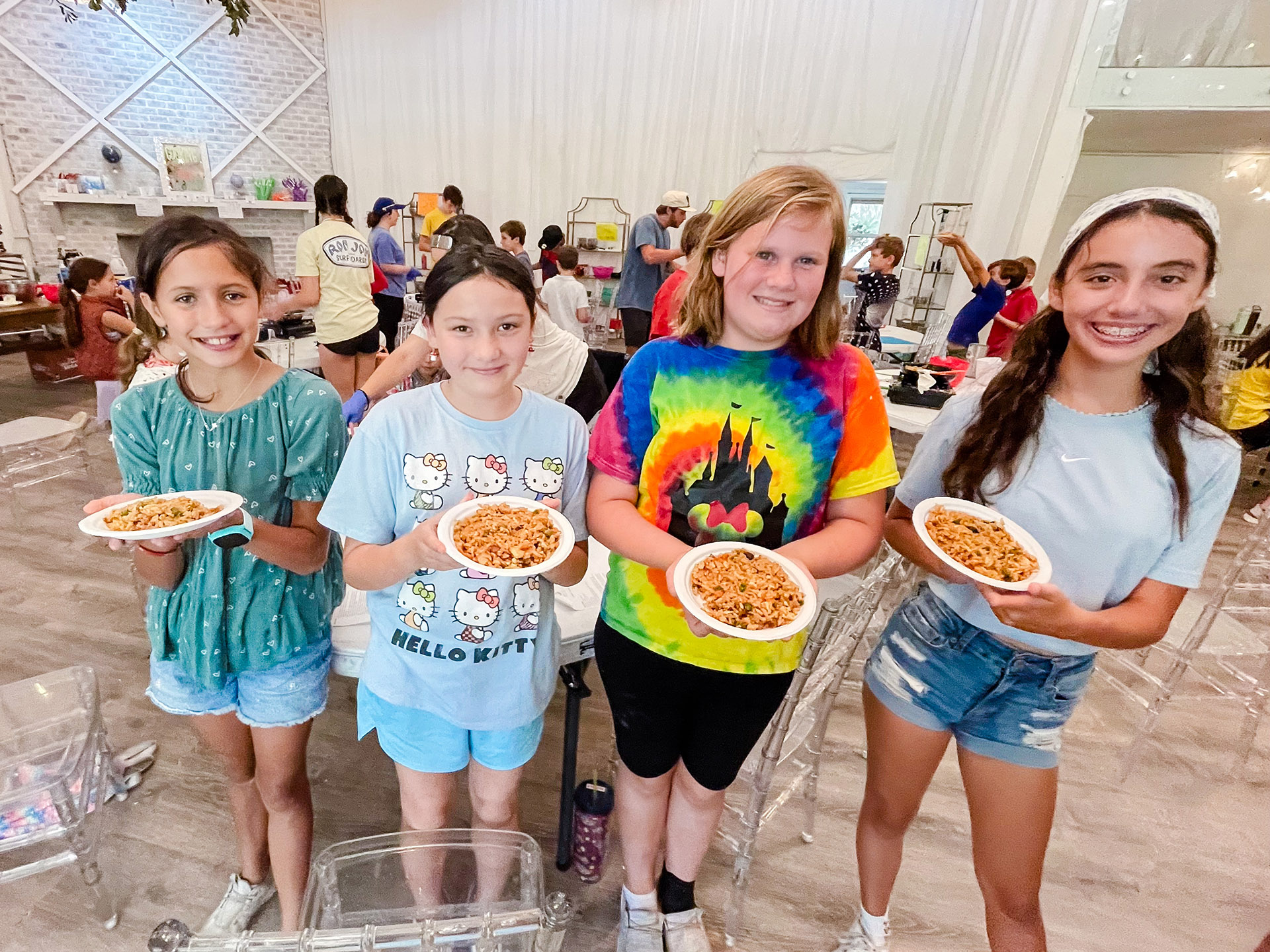 four girls proudly holding a bowl of fried rice that they prepared