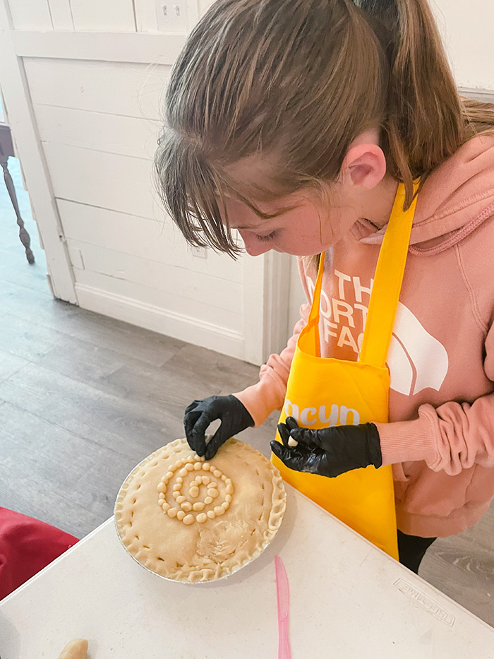 girl carefully decorating a pie