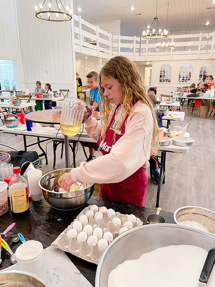 girl cracking eggs while making a recipe at Hewitt Oaks Kids Baking Camp