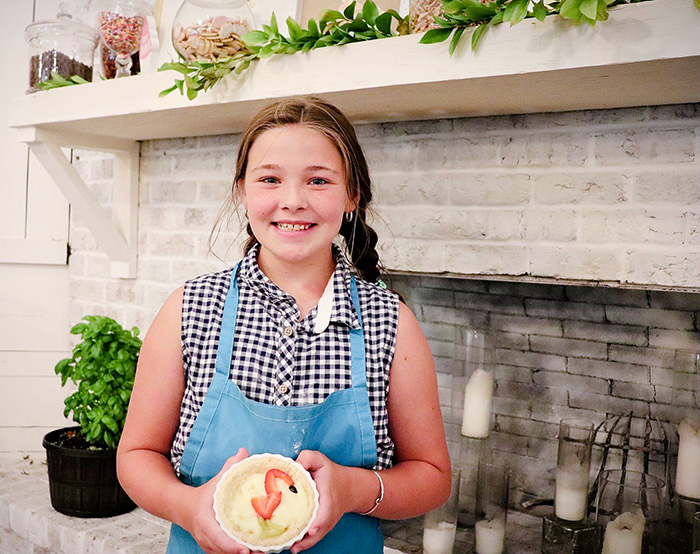 girl proudly holding a fruit tart that she made at Hewitt Oaks Kids Baking Camp
