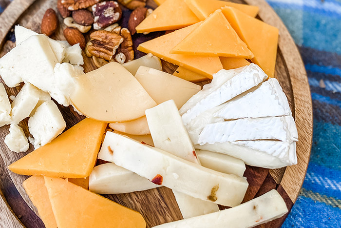 assorted cheeses and nuts arranged on a round tray