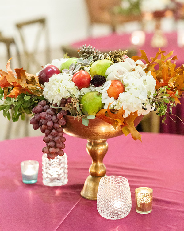 Fall floral arrangement with fruit, white hydrangea, and tree foliage