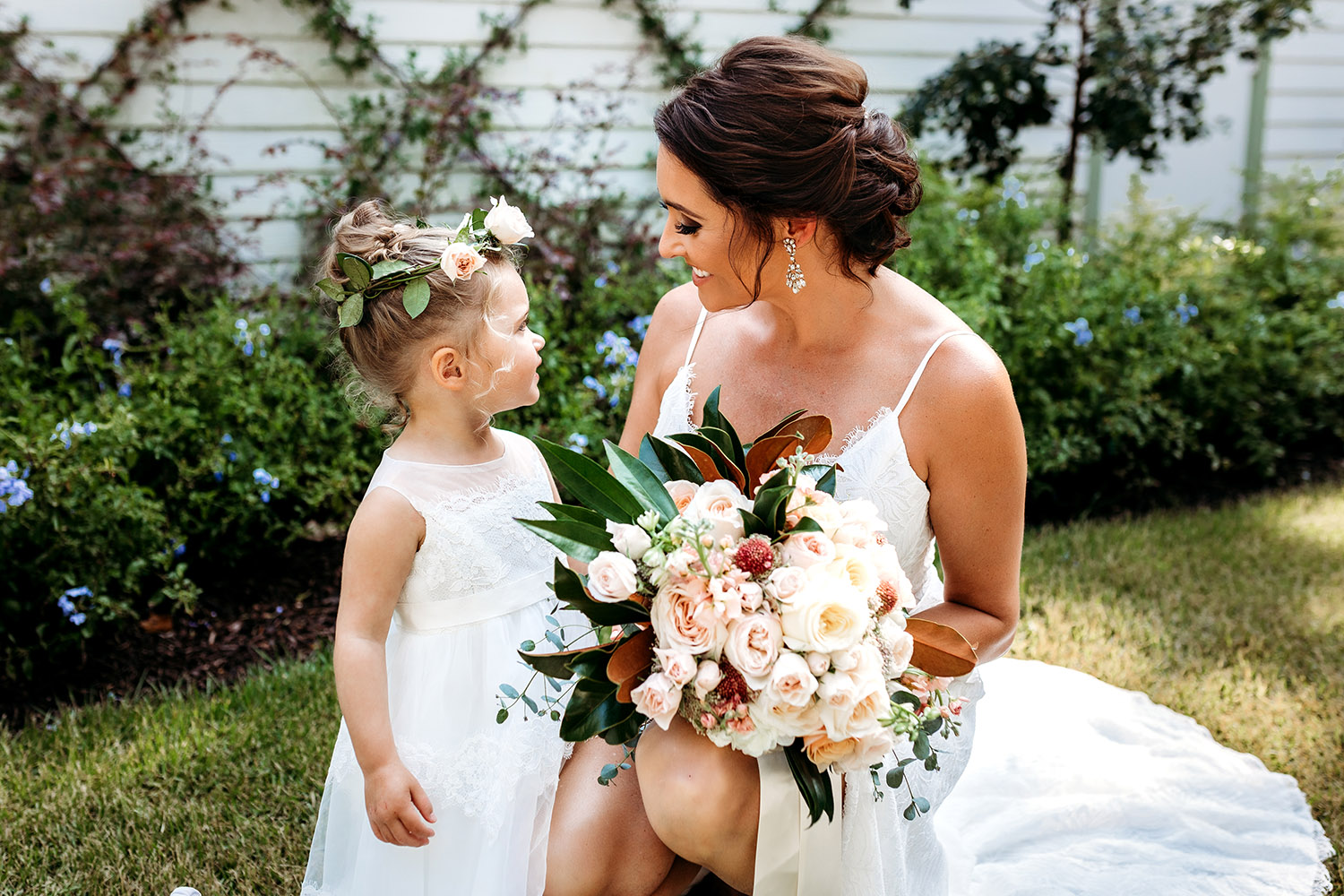 Flower girl and the bride holding a bouquet with magnolia leaves and roses