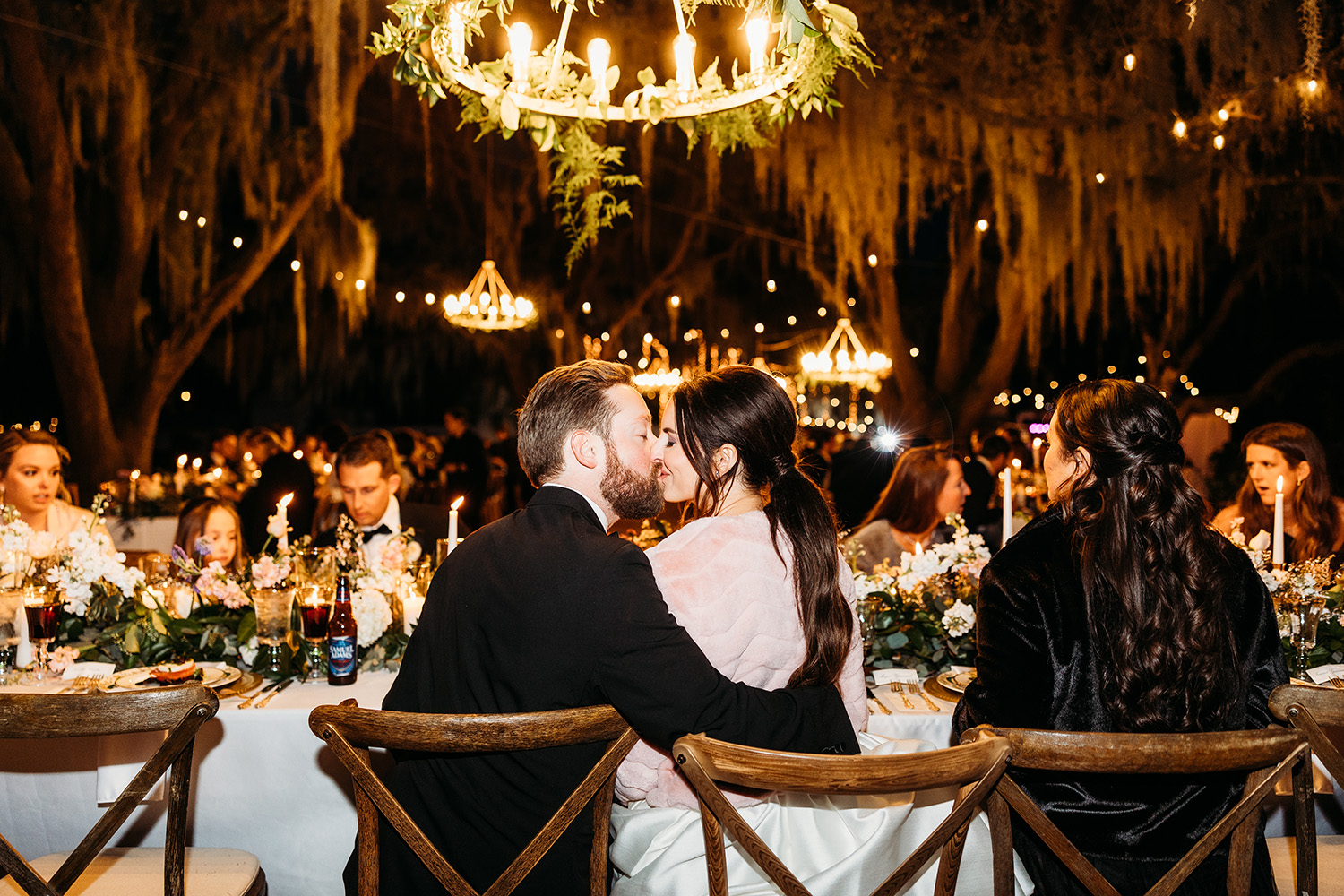 Bride and groom kissing while sitting.