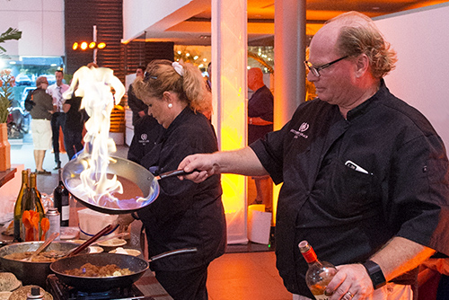 Chef Christopher Hewitt flambéing a dish in a large frying pan at an event