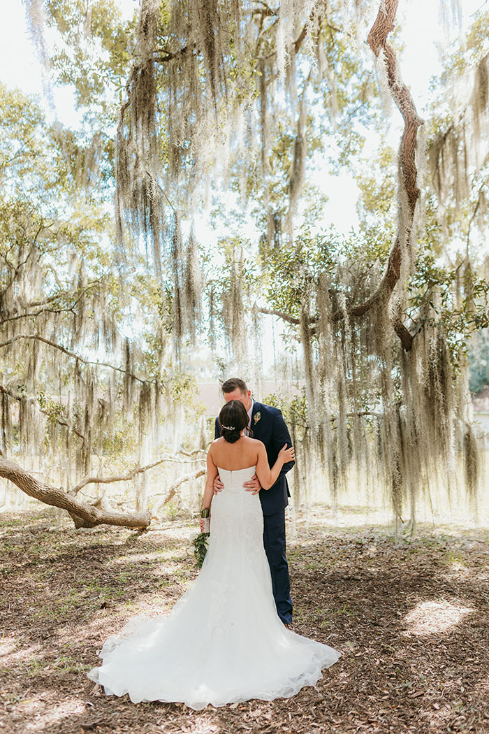 bride and groom kiss with a backdrop of low hanging live oak tree branches draped in spanish moss