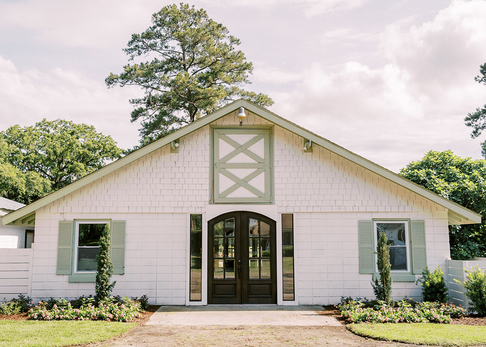 front view of Huling Hall, a one story, gabled building painted white with pale green trim