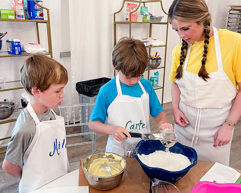 boys measure flour at baking camp while a counselor observes