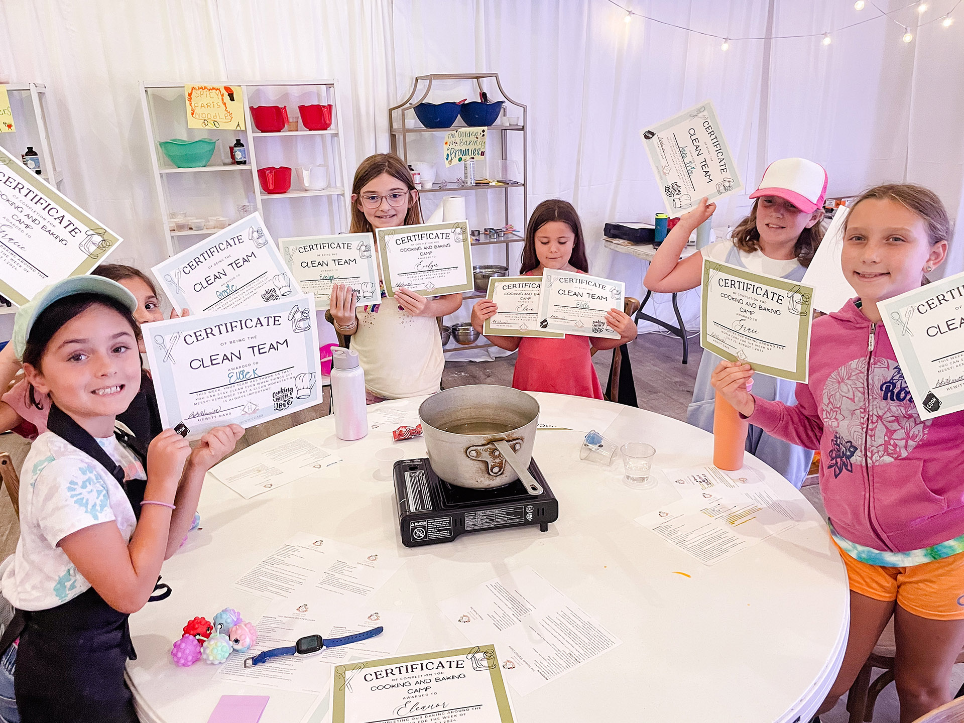 Kids hold up their award certificates at Hewitt Oaks Baking and Cooking Camp