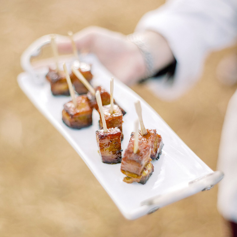 Bourbon Braised Pork Belly Lollipops on a tray served as butler-passed hors d'oeuvres