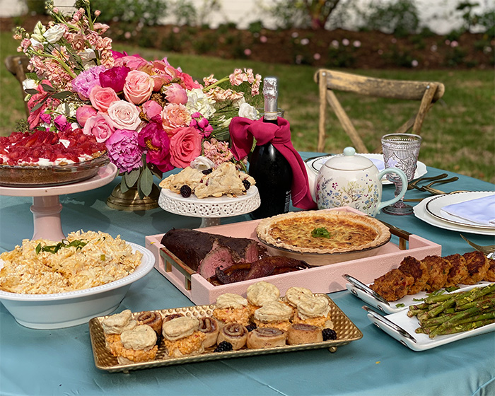 decadent brunch set on a table outdoors with a pink bouquet and bottle of Prosecco