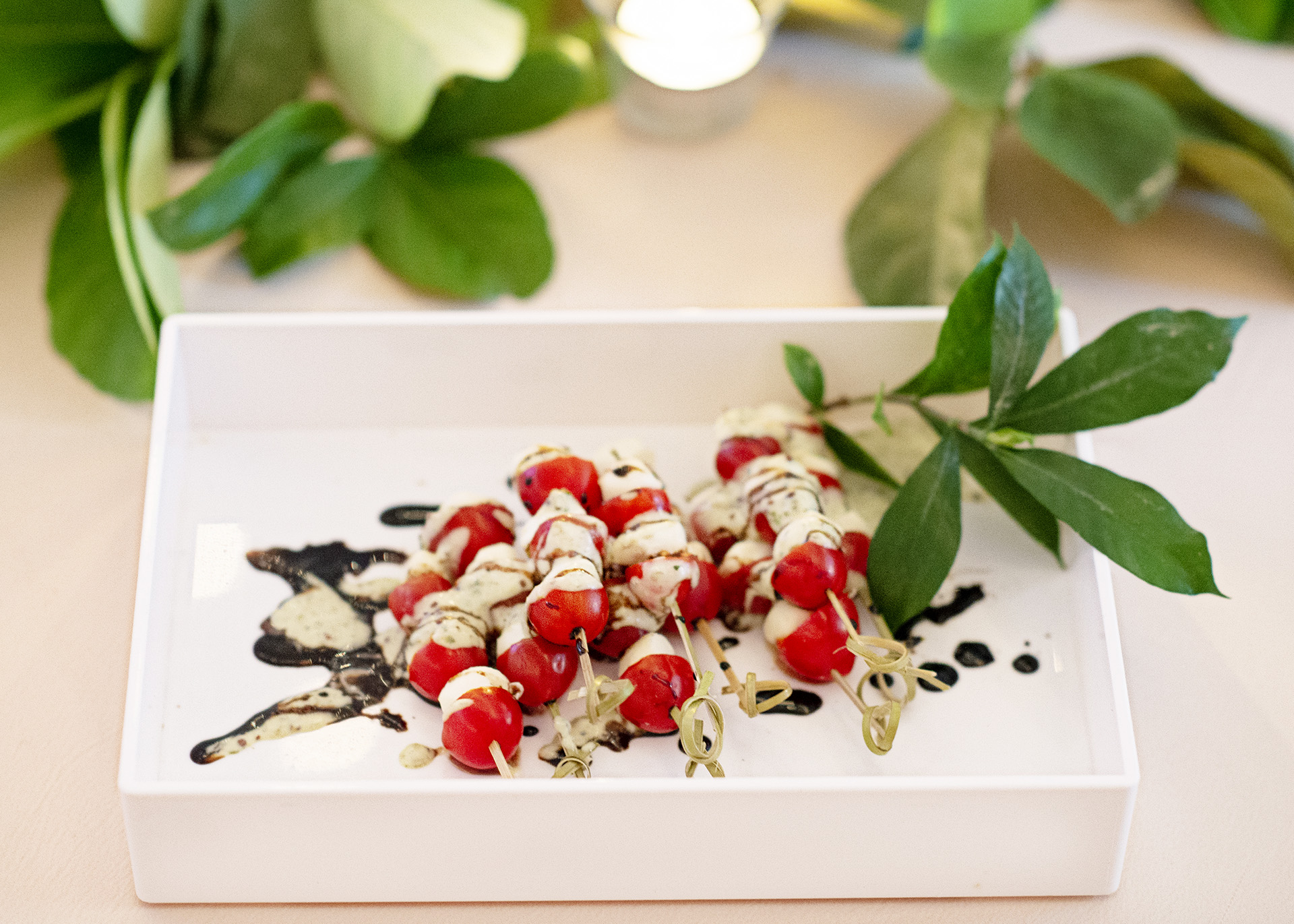 Caprese salad wands on a small tray with greenery garnish