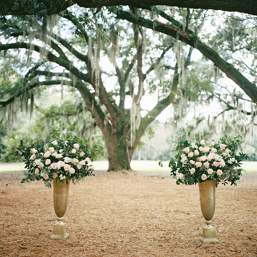 Elegant gold urns filled with pink and white roses, accented by natural greens