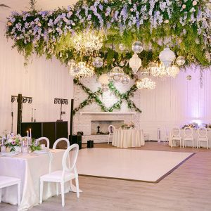 A dance floor illuminated by ceiling chandeliers adorned with floral decorations.
