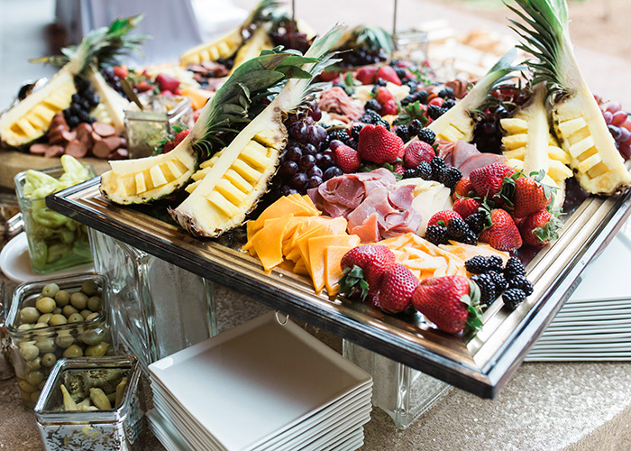 a bountiful display of pineapples, berries, meats, and cheeses arranged for a charcuterie display at a Lowcountry wedding reception