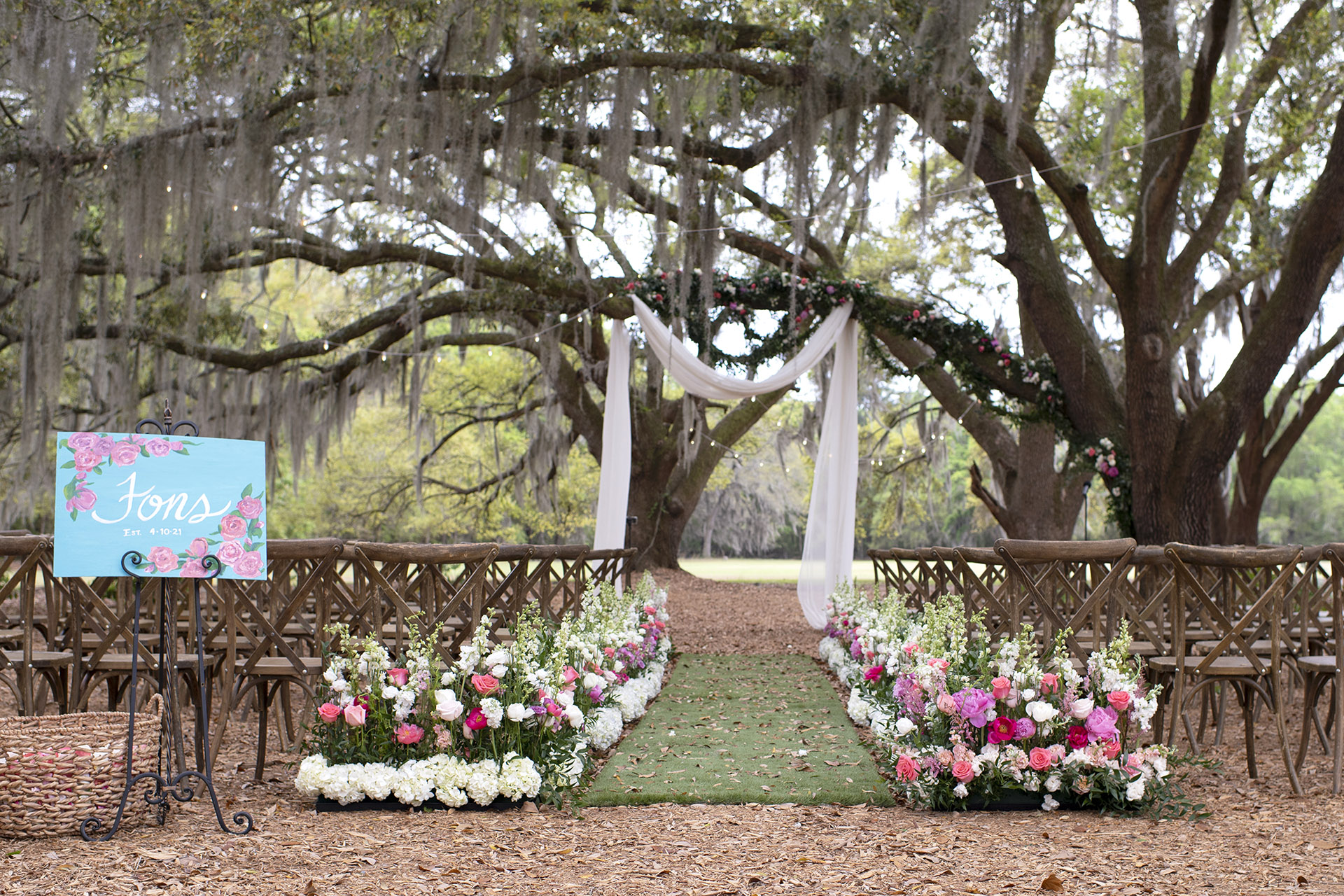 Angel Oak Canopy wedding ceremony with white chiffon draping at the altar and the aisle lined with pink and white spring florals