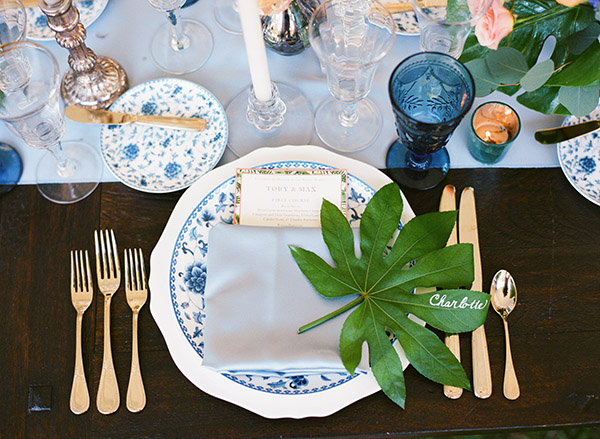 place setting with blue and white china, baby blue linens, and tropical leaf placecard